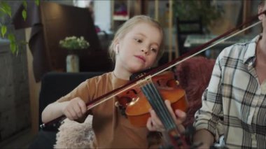 Çocuk keman çalmayı öğreniyor. Bir müzik öğretmeni yaylı telleri çalan bir kızı izliyor. Yüksek kalite 4k görüntü