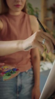 İki sevimli kız arkadaş stüdyoda duruyorlar, gülümsüyorlar ve birlikte resim çiziyorlar. Yüksek kaliteli FullHD görüntüler