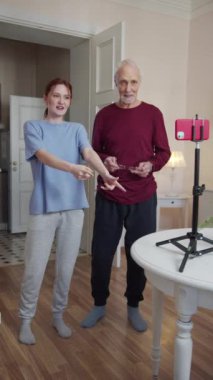 Yaşlı bir adam ve kadın tripodun üzerinde odanın ortasında telefonun önünde dikiliyorlar. Kız blogcu izleyicilerle derede iletişim kuruyor ve emekli de yardım ediyor. Yüksek kalite FullHD