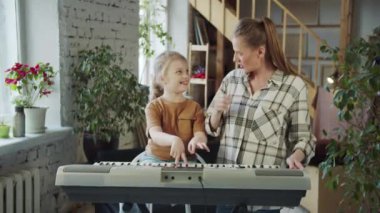 Kız annesi için piyano çalıyor, oyalanıyor ve dalga geçiyor. Yüksek kalite 4k görüntü