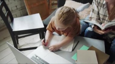 Kız kendi işiyle meşgul olan annesinin yanına resim çiziyor. Bir kadın not defterindeki notlara bakar ve onları bir dizüstü bilgisayardaki bilgilerle karşılaştırır. Yüksek kalite 4k görüntü