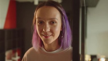 Pencerenin yanında duran genç bir kız öğrenci kameraya bakıyor ve gülümsüyor. Yüksek kaliteli FullHD görüntüler