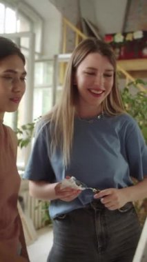 İki yakışıklı yetişkin kız resimlerini çizerken onları izliyor, gülümsüyor ve konuşuyorlar. Yüksek kaliteli FullHD görüntüler