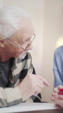 Bir emekli ve yetişkin kızı telefonlarındaki fotoğraflara bakıyorlar. Mutlu görünüyorlar. Yüksek kaliteli FullHD görüntüler