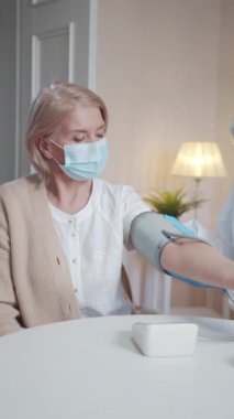 Doktor, tonometrenin kolunu bir emeklinin eline koydu. Cihazın düğmesine basıyor ve ölçmeye başlıyor.