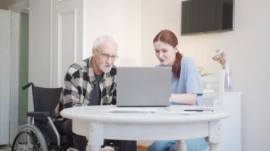 Sosyal hizmetlerden bir kadın, yaşlı bir adamın internet üzerinden bir şeyler almasına yardım ediyor. Yüksek kalite 4k görüntü