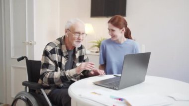 Kız yaşlı babasına kablosuz kulaklık verdi. Müzikten ve tekerlekli sandalyede dans etmekten hoşlanan bir adam. Yüksek kalite 4k görüntü