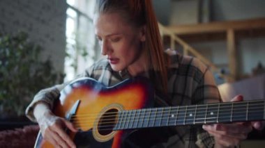 Bir kadın gitar çalmayı öğreniyor. Utangaç bir şekilde akorları çalar ve telleri çalar. O, internette bir video dersi izliyor. Ağır çekim, yakın çekim. Yüksek kalite 4k görüntü
