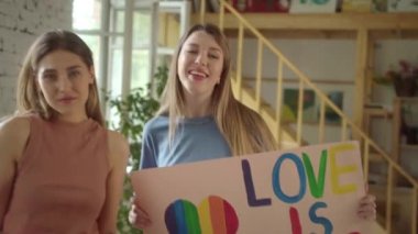 İki güzel genç kız ellerinde Igbt posterleriyle stüdyoda duruyor ve kameraya bakıyor. Yüksek kaliteli FullHD görüntüler