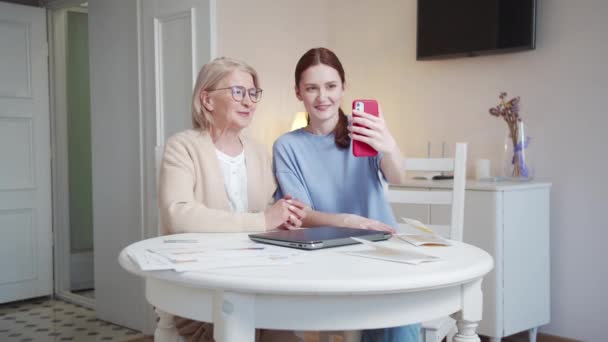 안경과 그녀의 친구와 할머니는 거실에 앉아있다 그들은 통화를 가족과 이야기 — 비디오