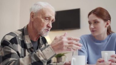 Kız üzgün bir emekliyle çay içiyor. O, onun hikayelerini ilgiyle dinler. Ağır çekim, yüksek kalite 4K görüntü