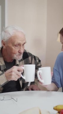 Kızı tekerlekli sandalyedeki yaşlı bir adamı ziyarete geldi. Masada birlikte çay içerler. Bardakları tokuştururlar. Yüksek kaliteli FullHD görüntüler