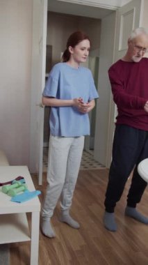 Yaşlı bir adam ve genç kızı eğitimle kollarını geliştiriyorlar. Dizüstü bilgisayardan egzersiz videoları izliyorlar. Yüksek kaliteli FullHD görüntüler