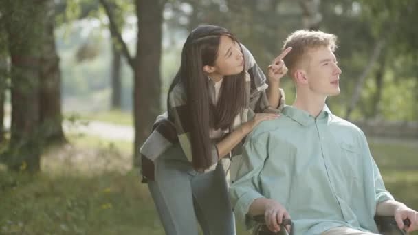 Słodka Azjatka Długimi Ciemnymi Włosami Pokazuje Niepełnosprawnego Młodego Mężczyznę Niebieskiej — Wideo stockowe