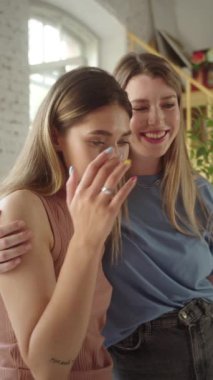 A young pretty lgbt couple is watching on a ready painting picture, smiling and hugging . High quality FullHD footage