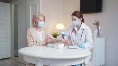 Beyaz önlüklü bir kadın ve yaşlı bir bayan banyoda bir masada oturuyorlar. Doktor ölçümleri kadının ısıyı ölçmek için yardım etmesini ister.