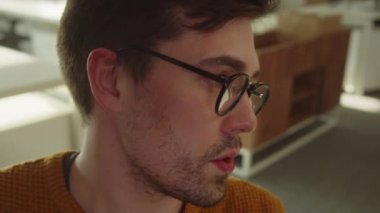 Sitting in the rest zone in the university, a young student is talking to his friend and smiling, slow motion close up. High quality FullHD footage