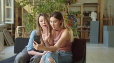 İki genç bayan video görüşmesinde arkadaşlarıyla konuşmayı bitirdiler, el sallayıp öpücük gönderdiler. Yüksek kaliteli FullHD görüntüler