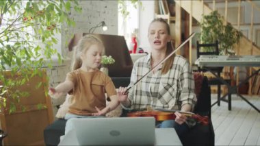 Bir çocuk genç bir kadına keman çalmayı öğretir. Kız annesine kemancılık hakkında bir video dersi veriyor. Orta Çekim