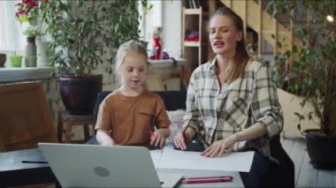 Genç bekar bir anne ve kızı video bağlantısı yoluyla öğretmene el sallıyor. Çizmeye başlamak için kağıt ve kalem seriyorlar. Yüksek kalite 4k görüntü
