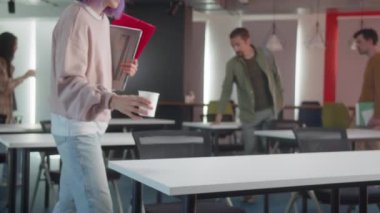 Enerjik genç öğrenciler sınıfa geliyorlar, birbirlerini selamlıyorlar ve masalarına oturuyorlar, seminer için hazırlanıyorlar, ağır çekimde. Yüksek kalite 4k görüntü