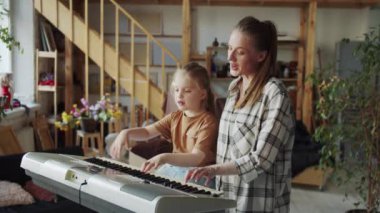 Anne ve kız sentezleyici çalıyor. Basit bir melodi çalıyorlar. Sonra bitip sarılırlar. Yüksek kalite 4k görüntü