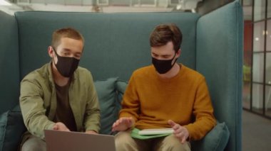 Üniversitenin dinlenme sahasında birlikte oturan genç öğrenciler, yavaş çekimde ortak projeleri hakkında tartışıyorlar. Yüksek kaliteli FullHD görüntüler