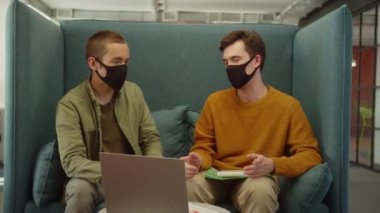 Üniversitenin dinlenme sahasında birlikte oturan genç öğrenciler, yavaş çekimde ortak projeleri hakkında tartışıyorlar. Yüksek kaliteli FullHD görüntüler