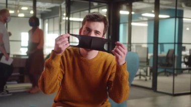 Üniversitenin giriş salonunda oturan beyaz bir öğrenci, yüzüne koruyucu bir maske takıyor ve yavaş çekimde kameraya bakıyor. Yüksek kalite 4k görüntü