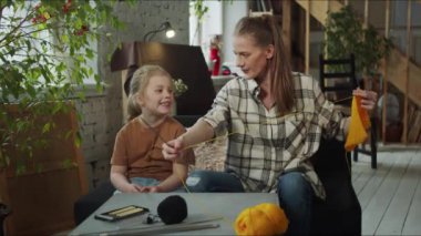 Ekose gömlekli anne kızıyla kanepede oturuyor. Bir kadın örgü örer ve kızına dikiş işinden bahseder. Yüksek kalite 4k görüntü
