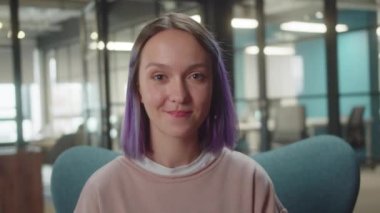 Üniversitede sandalyede oturan genç, sevimli bir öğrenci kameraya bakar ve gülümser, kapatır. Yüksek kalite 4k görüntü