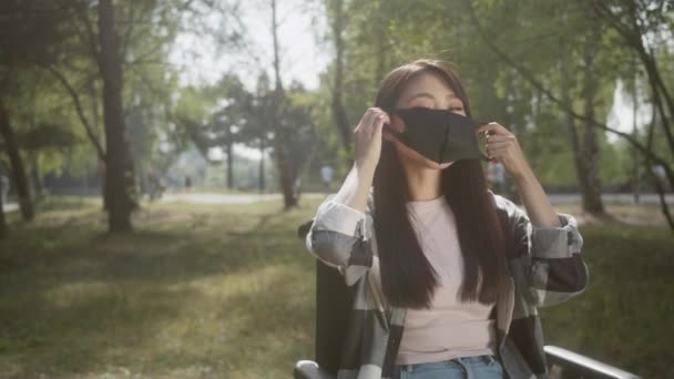 一位有着一头长长的黑头发的漂亮的亚洲残疾女士在公园里戴上了保护面具 高质量的4K镜头 — 图库视频影像