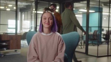 Üniversitede sandalyede oturan genç, sevimli bir öğrenci kameraya bakar ve gülümser, yavaşça yaklaşır. Yüksek kalite 4k görüntü