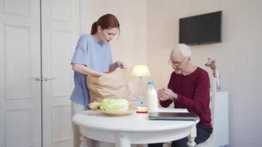 Kız torbalardan meyve ve sebze çıkarıyor. Masada oturan dedesine veriyor. - Ne? Yüksek kalite 4k görüntü