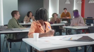 Çekici genç bir Afrikalı profesör seminere hazırlanıyor, öğrencileriyle konuşuyor ve birlikte gülümsüyorlar. Yüksek kalite 4k görüntü