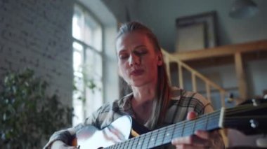 Uzaktan müzik dersi alan bir kız. O, gitar çalmaya çalışıyor. İşini iyi yapıyor ve gülümsüyor. Yüksek kalite 4k görüntü