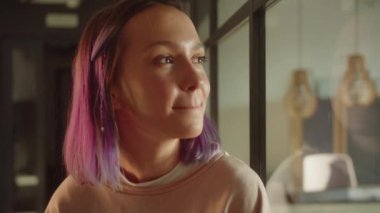 Genç bir kız öğrenci pencerenin yanında duruyor, uzaklara bakıyor ve hayaller kuruyor. Yüksek kaliteli FullHD görüntüler