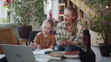 Annesi bir çocuğa okul sınavında yardım ediyor. Dersi bitirdiler ve memnuniyetle el ele tutuşarak odadan ayrıldılar. Yüksek kalite 4k görüntü