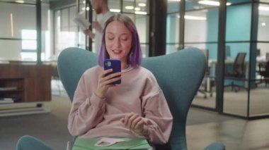 Genç, sevimli bir öğrenci sandalyede oturur ve internetten komik yazılar okur, yavaş çekimde kapatır. Yüksek kaliteli FullHD görüntüler