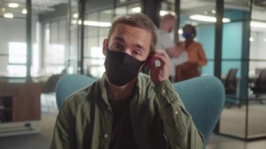 Haki gömlekli genç bir öğrenci koruyucu yüz maskesini çıkarıyor, kameraya bakıp gülümsüyor, ağır çekimde. Yüksek kalite 4k görüntü