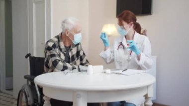 Yaşlı engelli bir kişi doktorların tavsiyelerini dinler. İki farklı ilaç öneriyor ve artıları ve eksileri hakkında konuşuyor. Yüksek kalite 4k görüntü