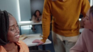 Enerjik genç öğrenciler üniversitede mola sırasında öğretmenleriyle konuşuyor ve gülümsüyorlar. Kapatın. Yüksek kalite 4k görüntü