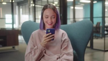 Genç bir kız öğrenci sandalyede oturur ve internette esprili yazılar okur, kapat. Yüksek kaliteli FullHD görüntüler