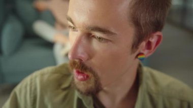 Sitting in the rest zone in the university, a young student is talking to his friend and smiling, slow motion close up. High quality FullHD footage