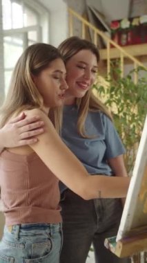 A young pretty lgbt couple is watching on a ready painting picture, smiling and hugging . High quality FullHD footage