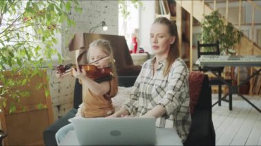 A woman is engaged in music with a child. They called with a tutor via the Internet. High quality 4k footage