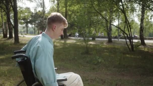 Zdravotně Postižený Muž Modré Košili Projíždí Invalidním Vozíku Veřejným Parkem — Stock video