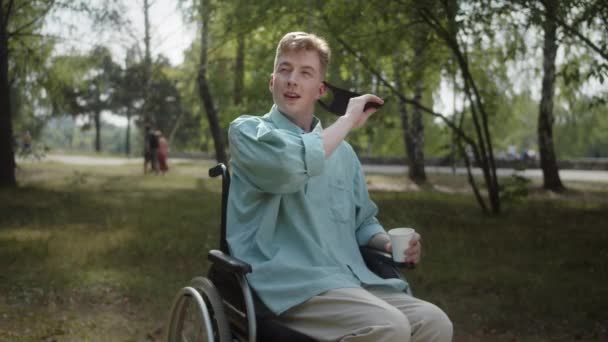 공원에서 휠체어를 잘생긴 장애인 남자가 얼굴에 보호용 마스크를 카메라를 웃으며 — 비디오