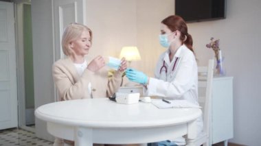 The doctor helped the pensioner put on a protective mask. Start of patient examination. High quality 4k footage