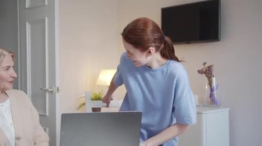 Kız, yaşlı bir bayanın oturduğu geniş bir oturma odasına girer. Yanında bir kadın oturuyor ve emekliye bilgisayarın nasıl kullanılacağını dikkatlice ve neşeyle anlatıyor. Yüksek kalite 4k